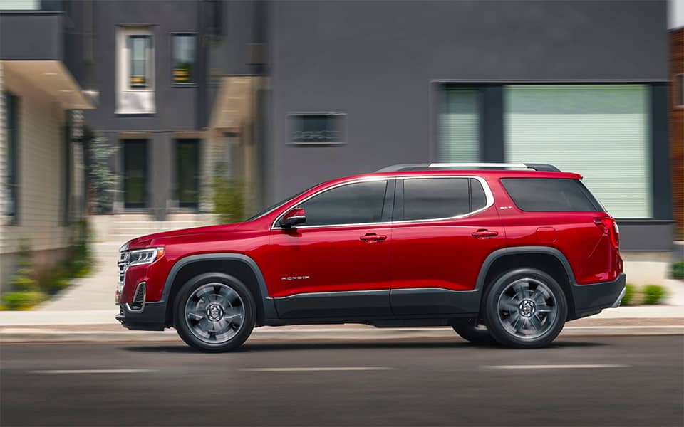 A sideview of a red Acadia on a road